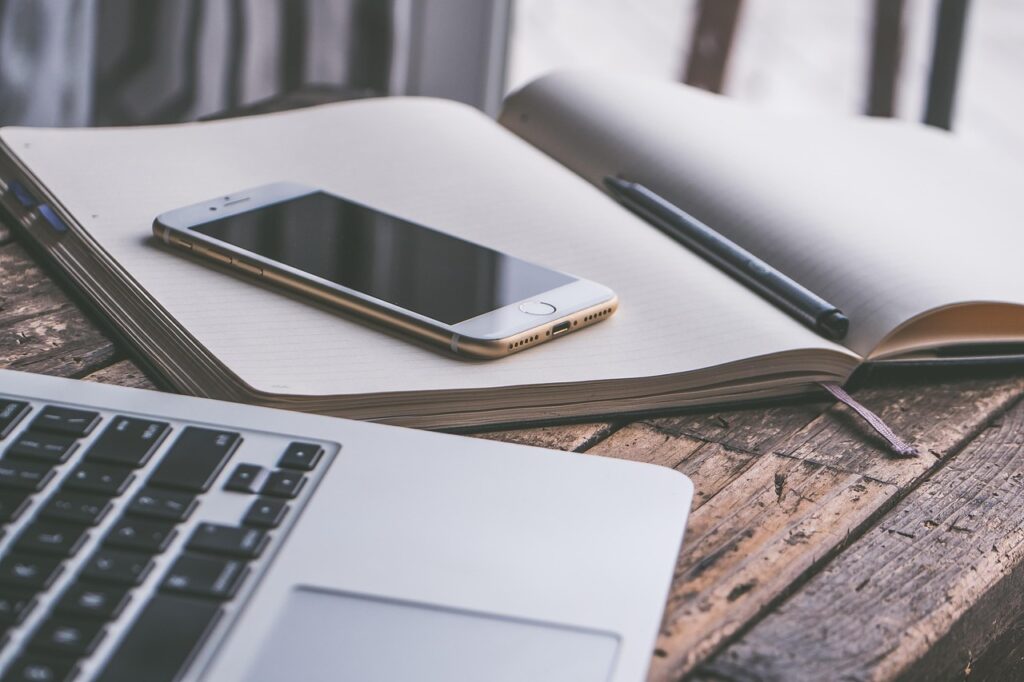 Picture of a desk with a phone, notebook and laptop on it